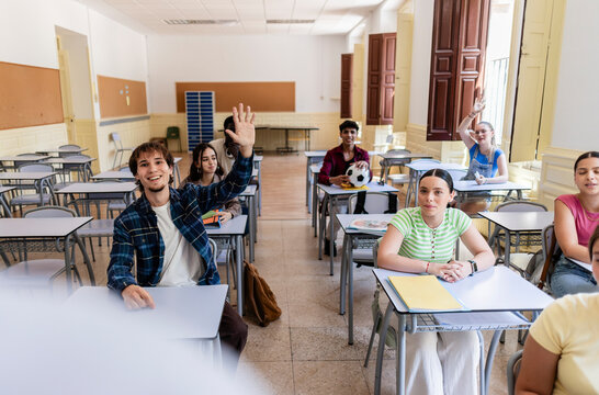Students raising hands showing active classroom participation