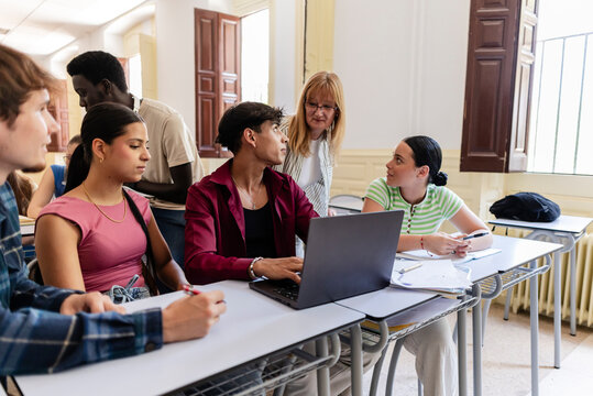 Teacher guiding diverse students learning in university classroom