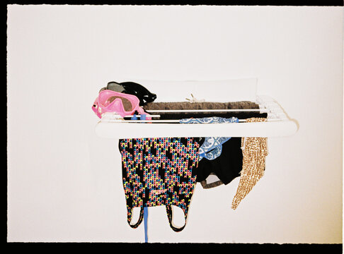 Swimwear and scuba mask drying on white rack