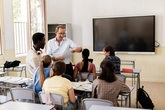 Teacher explaining lesson to diverse students group in