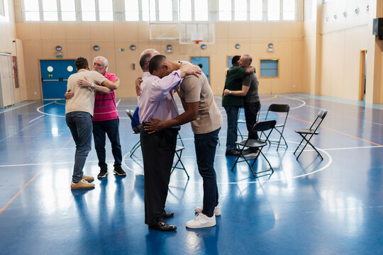 Diverse men hugging offering emotional support in group