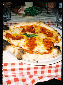 Italian pizza with basil on red checkered tablecloth
