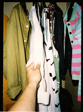 Hand choosing clothes from a full wardrobe closet