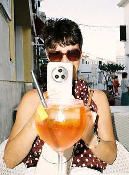 Person capturing moment, cocktail, enjoying summer vacation outdoors