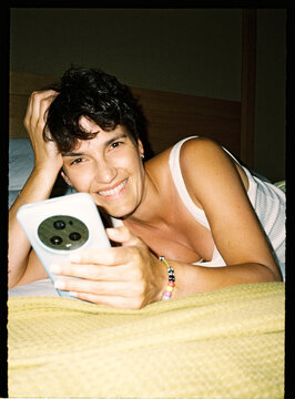 Person relaxing in bed at home using smartphone