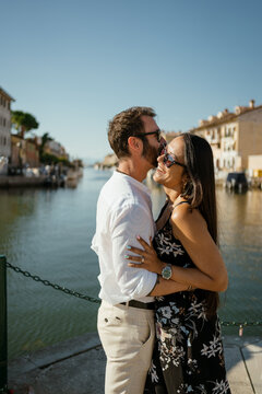 Couple hugs and have fun along a sea promenade in town