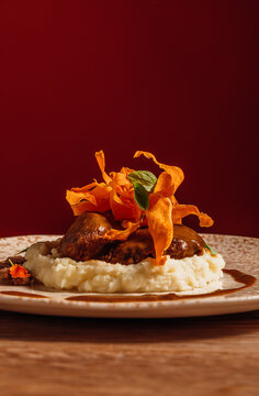 Close-up of gourmet braised meat with sweet potato chips