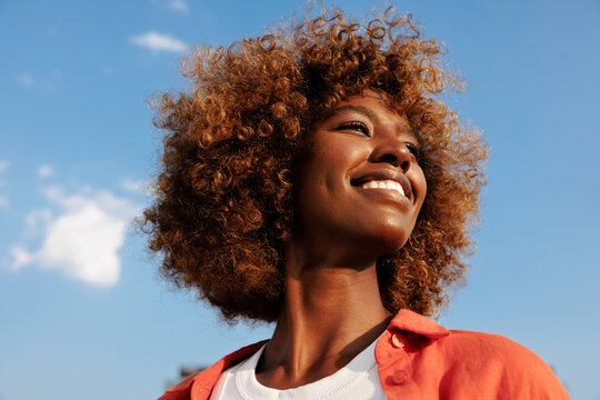 Smiling woman under blue sky in summer sunlight