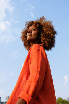 Woman portrait in orange shirt against blue sky