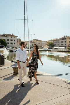 A couple walking hand in hand by the town harbour during vacation