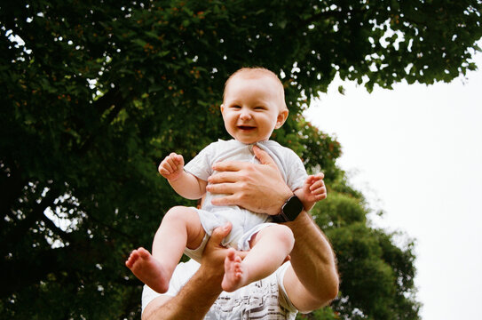 Child is being held and smiling outdoors