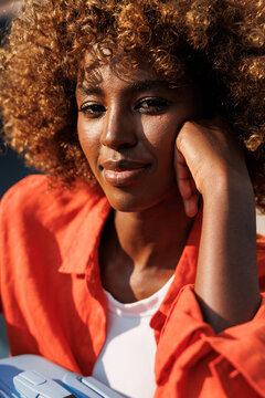 Woman portrait in orange shirt resting on hand