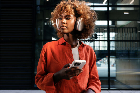Woman with headphones checking smartphone in modern building
