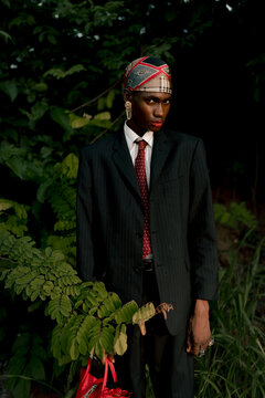 Fashion portrait of young Black model in tailored suit outdoors.