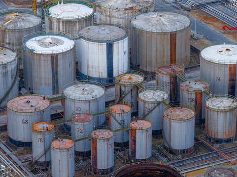 Aerial view of a fuel depot with numerous large industrial storage tanks featuring weathered surfaces and numbered labels in an industrial facility. Rome, Lazio, Italy.