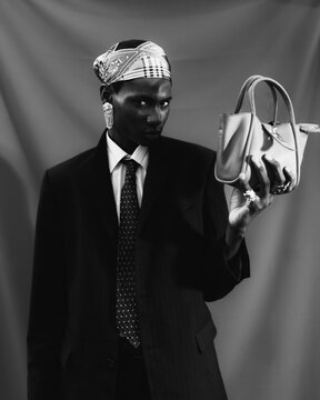 Black and white fashion portrait holding leather handbag.
