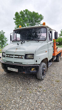 Grey ZiL-5301 Bychok tow truck with an orange bed and Russian license plate on a gravel lot near Cherkessk, historic truck, Karachay-Cherkessia, Russia 11.05.25