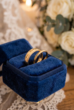 Two polished gold wedding bands intertwined inside elegant velvet ring box, luxurious wedding aesthetic, refined jewelry craftsmanship, romantic symbol of devotion and union. Close-up.