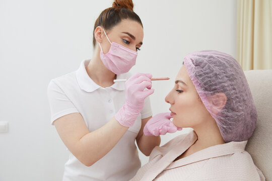 Cosmetologist drawing mark on client face to prepare for rejuvenation treatment