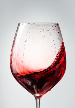Wine glass with red liquid frozen in movement.