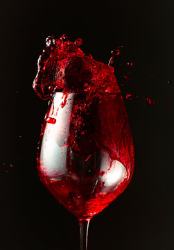 An image of red wine being splashed into a glass.