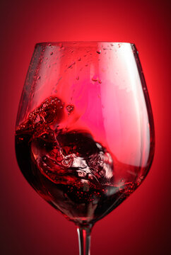Wine glass with red liquid frozen in movement.