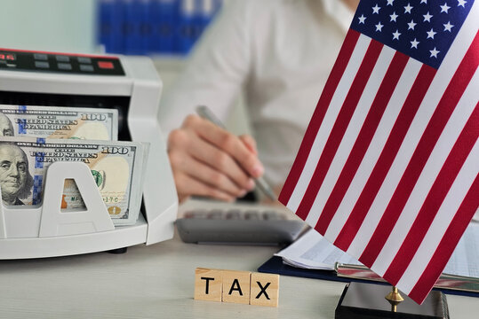 Tax preparation process at an office with cash, calculator, and American flag concept