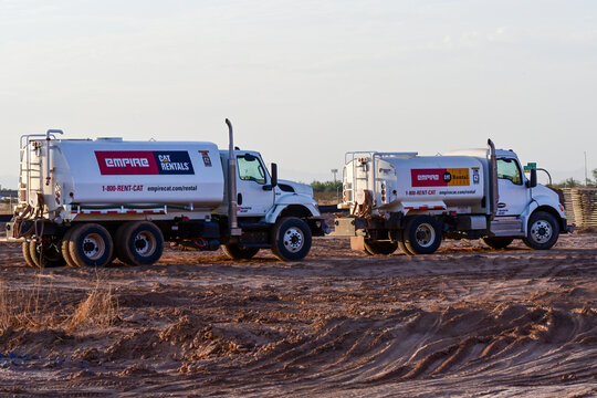Two water trucks parked at a large commercial development site, illustrating dust control, construction support, site preparation, and large-scale building operations