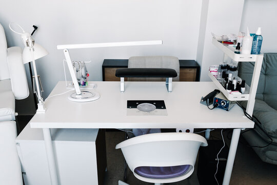 Front view of a manicure workstation with lamp, dust collector, tools and polish bottles. Clean salon setup for nail care services and beauty business