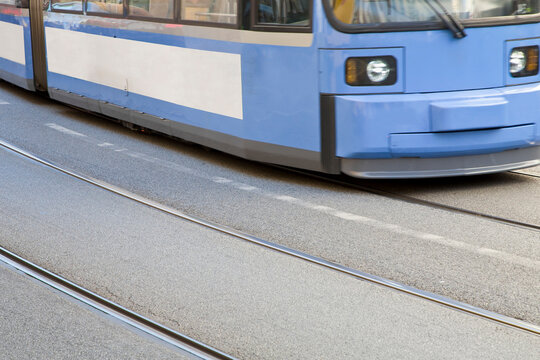 URBAN ELECTRIC TRAM TRAVELING ON RAILS EMBEDDED IN A CITY STREET - ECO FRIENDLY PUBLIC TRANSPORT AND RAIL INFRASTRUCTURE REPRESENTING MODERN URBAN TRANSIT AND SUSTAINABLE MOBILITY