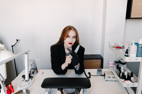 Nail technician sits at an equipped manicure workstation with drill, file and salon supplies. Beauty business concept for professional services and nail care