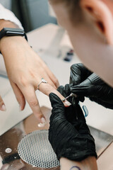 Obraz premium Close view of a nail technician using a rotary drill on a clients fingernail. Professional manicure concept for shaping, preparation, precision and salon care