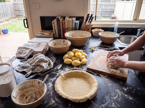 Person preparing homemade pie dough in a messy kitchen
