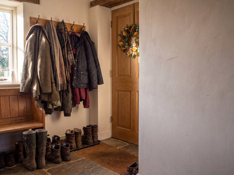 Rustic entryway with coats, boots, and a holiday wreath