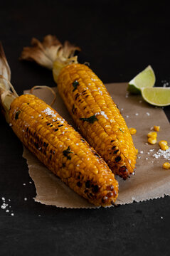 Charred corn on the cob with sea salt and lime, dark moody bbq food photo