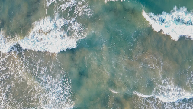 Top down aerial drone view of turquoise ocean water surface with white foam splashing waves for aquatic backdrop stock photo