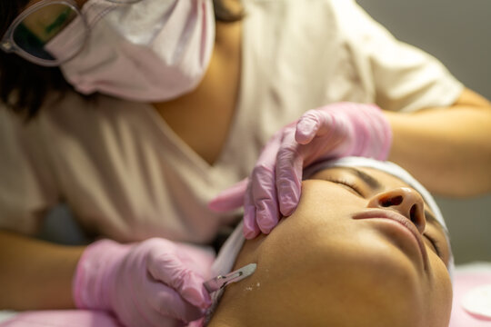 Professional performing facial cosmiatrics treatment on client
