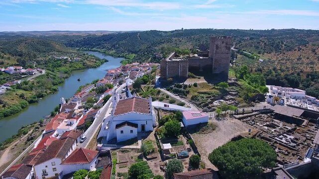 Stunning aerial footage revealing the historic town of mertola with its medieval castle and whitewashed houses, beautifully situated on a hill overlooking the winding guadiana river in portugal