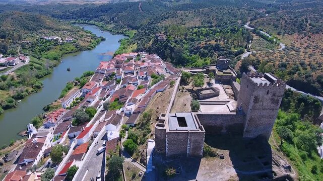 High aerial view of the historic village of mertola and its medieval castle overlooking the guadiana river in the alentejo region of southern portugal on a sunny day with a blue sky