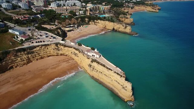 Aerial view circling the chapel of nossa senhora da rocha, a historic religious building perched on a dramatic cliff in armacao de pera on the beautiful algarve coast of portugal