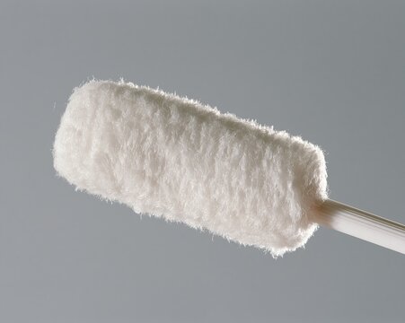 White, fluffy swab with wooden handle against gray background.