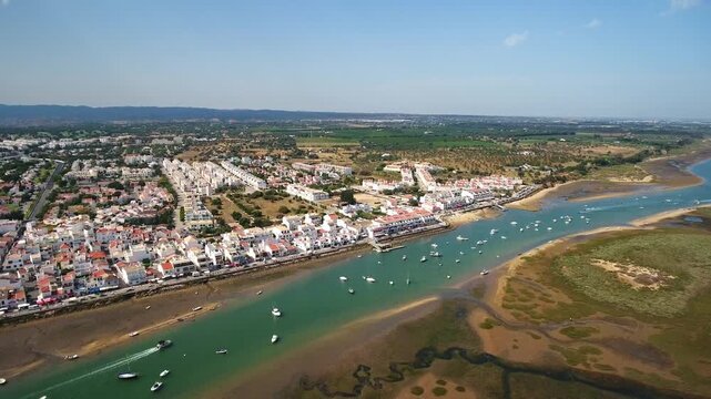 Stunning aerial shot slowly panning over the charming fishing village of cabanas de tavira and its beautiful lagoon, part of the ria formosa natural park in the algarve region of portugal