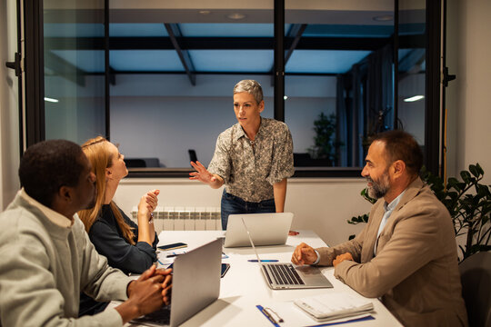 Confident female leader guiding team meeting in modern office