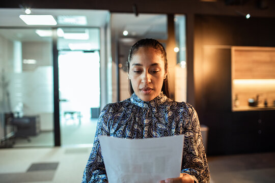 Businesswoman reading document in modern office