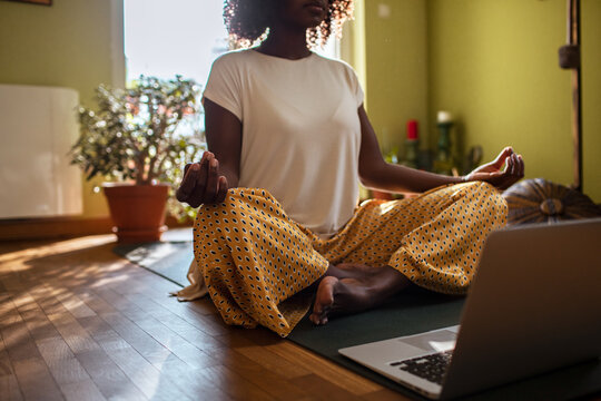 Woman meditating with laptop at home