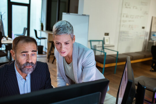 Two business colleagues reviewing data on computer in modern office