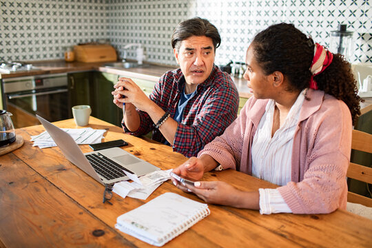 Concerned couple reviewing bills at kitchen table