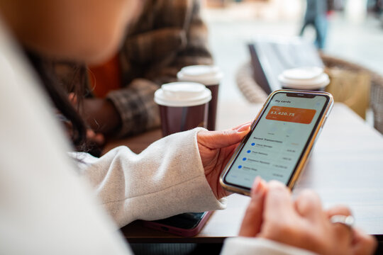 Woman checking account balance on smartphone at coffee shop
