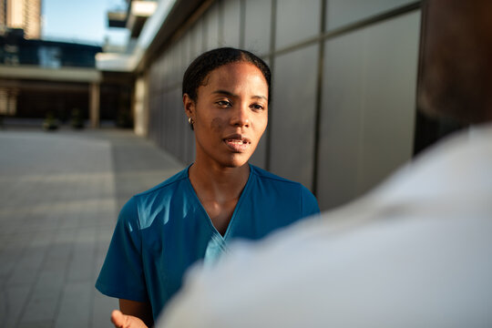 Young nurse talking with colleague outside hospital