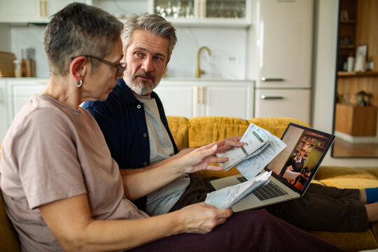 Senior couple reviewing bills during video call at home